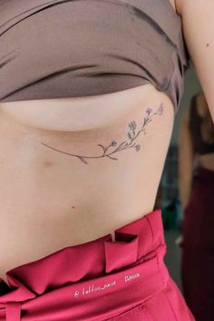 a woman's stomach with a small flower tattoo on her left side ribcage