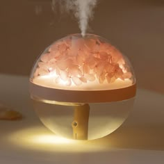 an air humider sitting on top of a table with steam coming out of it