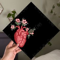 a person holding up a card with a heart and flowers on it in front of a bed