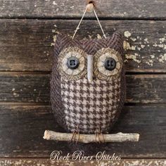 an owl ornament hanging on a wooden wall with black and white checkered fabric