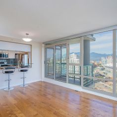 an empty living room with hardwood floors and large windows looking out onto the cityscape