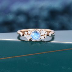 a ring with an oval blue stone surrounded by small white diamonds on a green surface