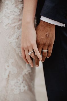 a close up of two people holding hands with rings on their fingers and wearing wedding bands