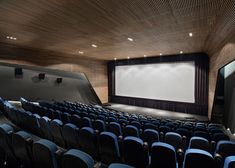 an empty theater with blue chairs and a projector screen