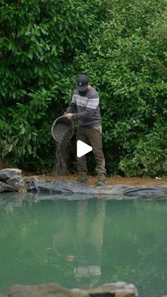 a man standing in front of a pond holding a net