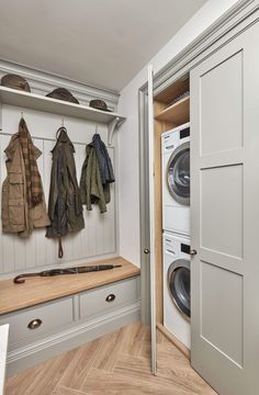 a washer and dryer in a room with white cabinets, wood flooring and open doors