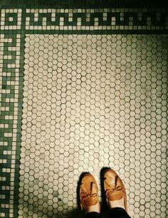 a person standing in front of a tiled floor with their feet up on the ground