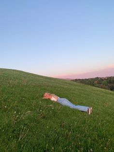 a person laying in the grass on top of a hill