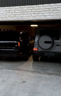 two vehicles are parked in a garage next to each other and one is black, the other is white