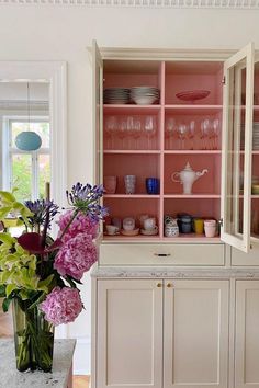 a vase filled with flowers sitting on top of a wooden table next to a cabinet