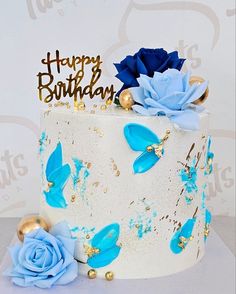 a birthday cake decorated with blue flowers and gold decorations