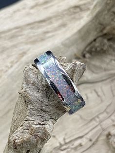 This beautiful handcrafted Stainless Steel comfort band is a real conversation starter! It features a blue Ice Opal inlay in the center of the ring. The crushed Opal is placed by hand, incased in resin, and then finished and polished to a brilliant shine. Each ring I make is truly unique and no two are ever the same. These rings are made to order and are available in several sizes. Please allow 3-5 days for me to complete your ring. I do custom orders and if you have a different ring material or Luxury Opal Inlay Ring For Gift, Unique Wedding Band Sets, Real Conversation, Fashion Rings Silver, Blue Opal Ring, Opal Band, Lapis Ring, Womens Ring, Magical Jewelry