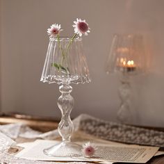 a glass vase with flowers in it sitting on a table next to an open book