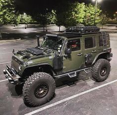 a green jeep is parked in a parking lot at night with its lights turned on