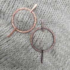 two rose gold hoop earrings sitting on top of a gray blanket