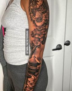 a woman with a tiger and flowers tattoo on her arm is standing in front of a door