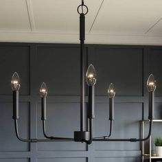 a black chandelier with five lights hanging from it's sides in a room