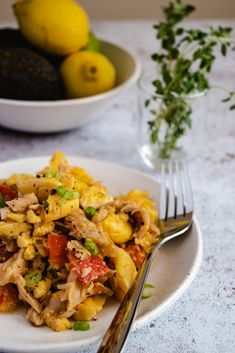 a white plate topped with pasta next to a bowl of lemons and two forks