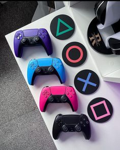 four video game controllers sitting on top of a white table next to some stickers