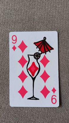 a playing card with an image of a wine glass and umbrella on the front side