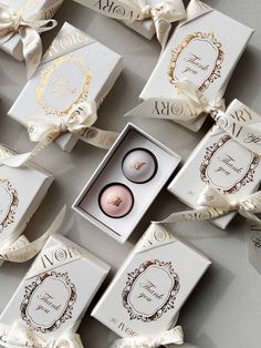 two wedding rings are in a box surrounded by other boxes with ribbons and bow ties