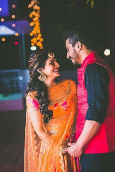 a man and woman standing next to each other in front of a building at night