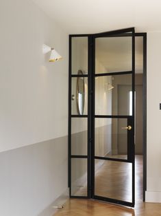 an empty room with wooden floors and glass doors on the door, looking into another room