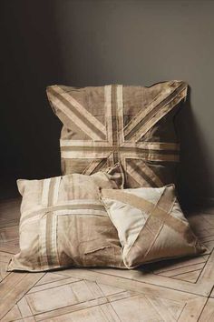 two pillows sitting on the floor in front of a wall with an union jack design