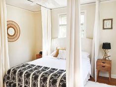 a bedroom with four poster bed and white walls