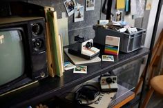 an old tv sitting on top of a wooden table next to a desk with pictures and other items