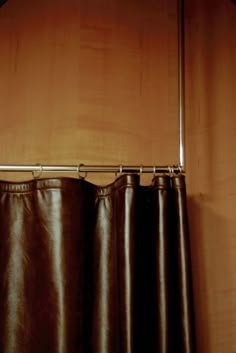 a brown curtain hanging on the side of a wooden wall next to a metal rod