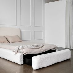 a bed that is made up with white sheets and blankets on top of the bed