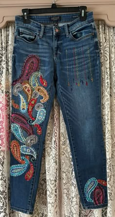 a pair of jeans with colorful embroidered designs on them