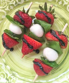 strawberries and marshmallows are arranged on skewers with green leaves