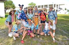 a group of people standing next to each other in front of a building with mickey ears on