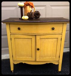 a yellow cabinet with some pumpkins on top