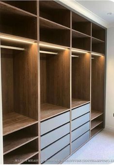 an empty walk in closet with wooden shelves and drawers