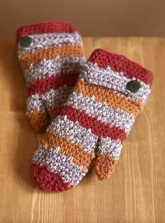 two crocheted mittens sitting on top of a wooden table