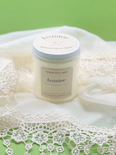 a jar of cream sitting on top of a white lace