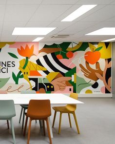 an office with colorful wallpaper and chairs in front of a table that is surrounded by flowers