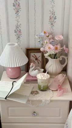 there is a white vase with pink flowers on it and a lamp next to it