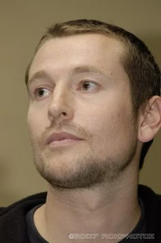 a close up of a person wearing a black shirt and looking off to the side