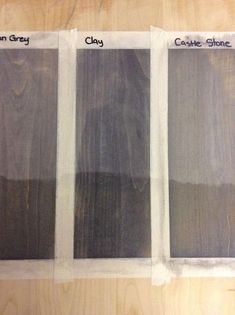 three different shades of gray paint sitting on top of a wooden table