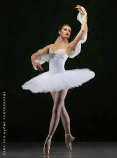 a ballerina in white tutu and veil posing for the camera with her arms outstretched