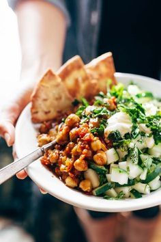 a person is holding a plate with food on it and bread in the other hand