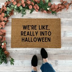 someone standing in front of a door mat that says, we're like really into halloween