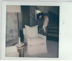 an old photo of two women and a child in a living room with white furniture