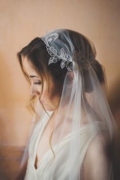 a woman with a veil on her head wearing a wedding dress and hair combs