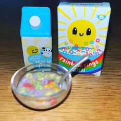 a bowl of cereal sitting on top of a wooden table next to a box and spoon