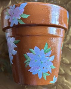 an orange flower pot with blue flowers painted on it